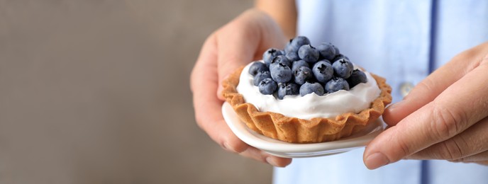 Image of Woman holding plate with blueberry tart, closeup view with space for text. Banner design