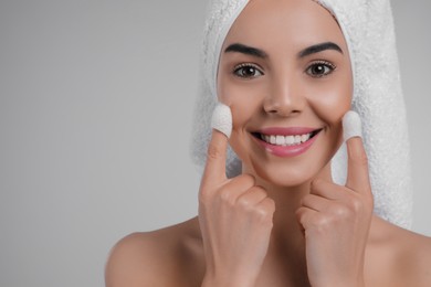 Woman using silkworm cocoons in skin care routine on light grey background. Space for text