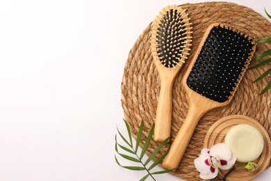 Wooden hairbrushes, solid shampoo, orchid flowers and leaves on white background, flat lay. Space for text