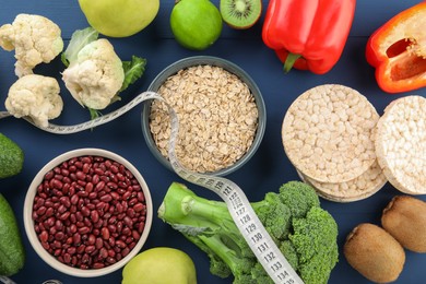 Healthy diet. Different products and measuring tape on blue wooden table, flat lay