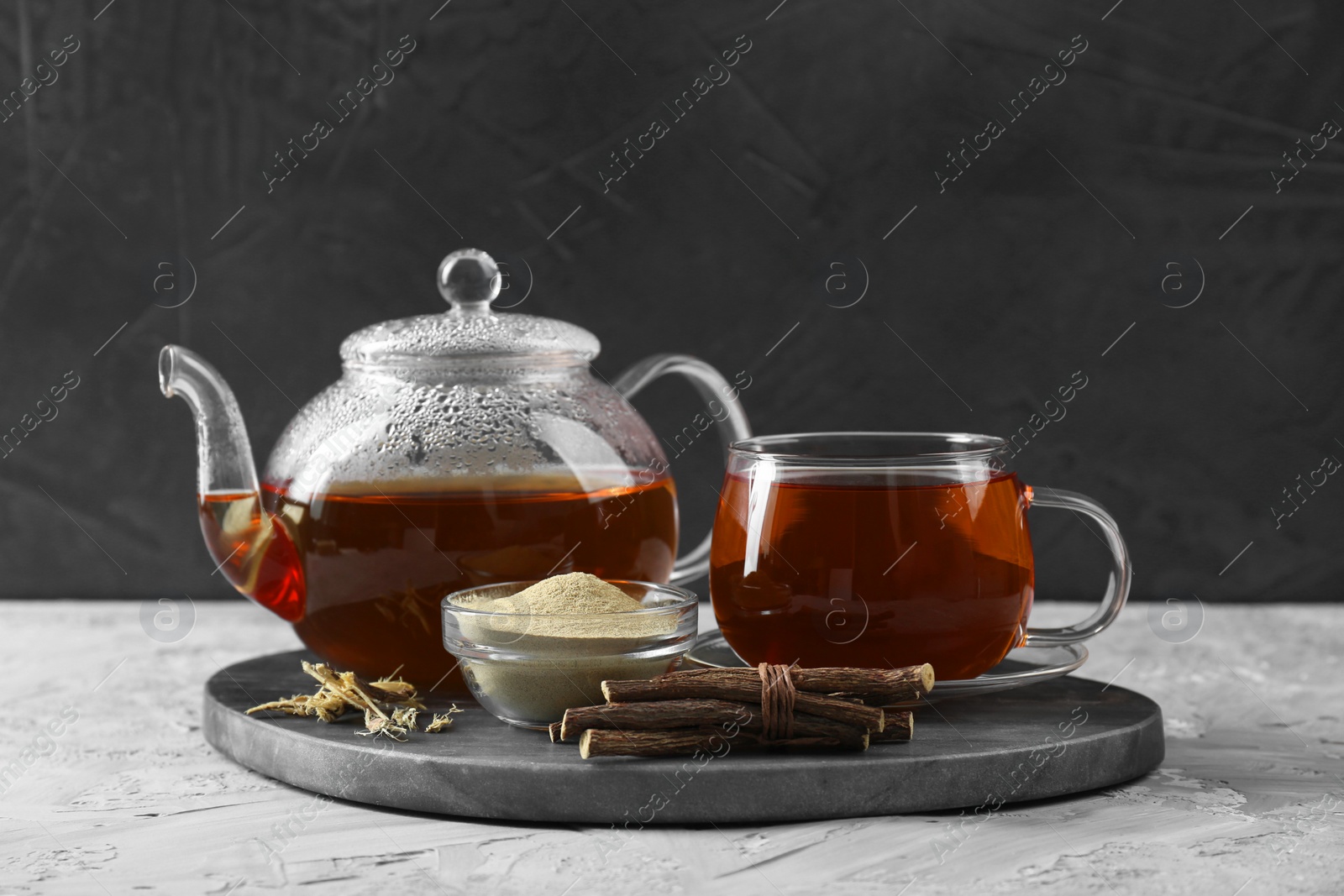 Photo of Aromatic licorice tea, dried sticks of licorice root and powder on light gray textured table