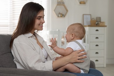 Photo of Happy young mother with her baby in armchair at home