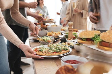 Photo of Woman taking slice of pizza from buffet indoors, closeup. Brunch table setting