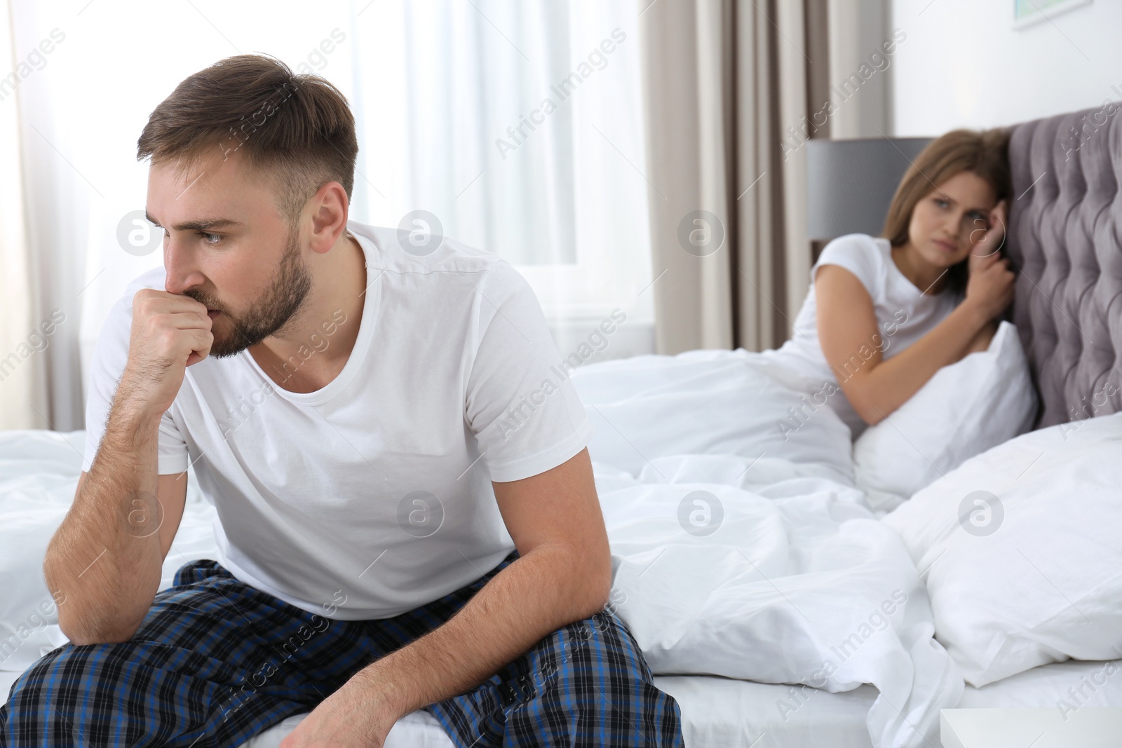 Photo of Young couple with relationship problems ignoring each other in bedroom