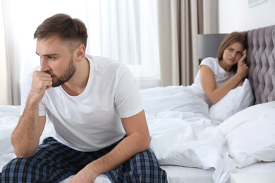 Photo of Young couple with relationship problems ignoring each other in bedroom