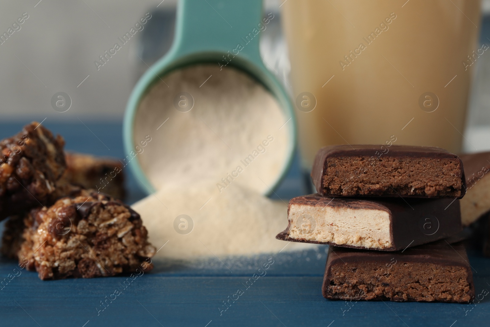 Photo of Different energy bars and protein powder on blue wooden table, closeup