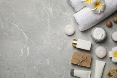 Photo of Flat lay composition with towels and skin care products on light grey marble background, space for text