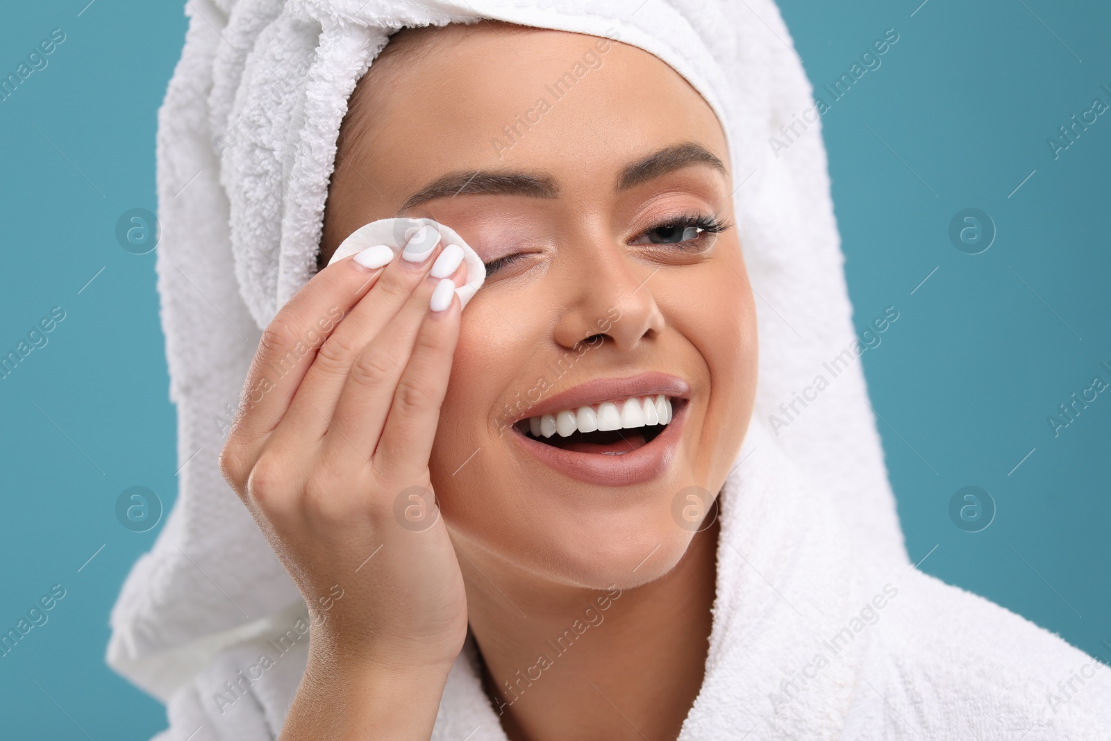 Photo of Beautiful woman removing makeup with cotton pad on light blue background