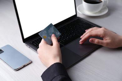 Photo of Online payment. Woman with laptop and credit card at white wooden table, closeup