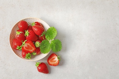 Photo of Bowl with ripe strawberries on light background, top view