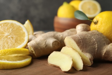 Photo of Cut ginger and lemon on wooden board, closeup