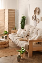 Stylish living room interior with comfortable wooden sofa and beautiful houseplants