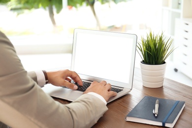 Photo of Man in office wear using laptop at table indoors