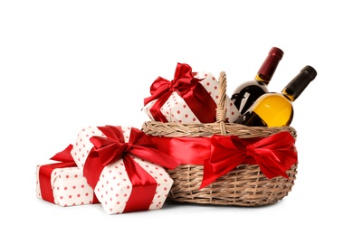 Festive basket with bottles of wine and gifts on white background