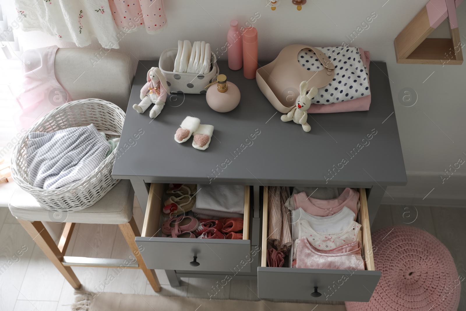 Photo of Open cabinet drawers with baby shoes and clothes in child room