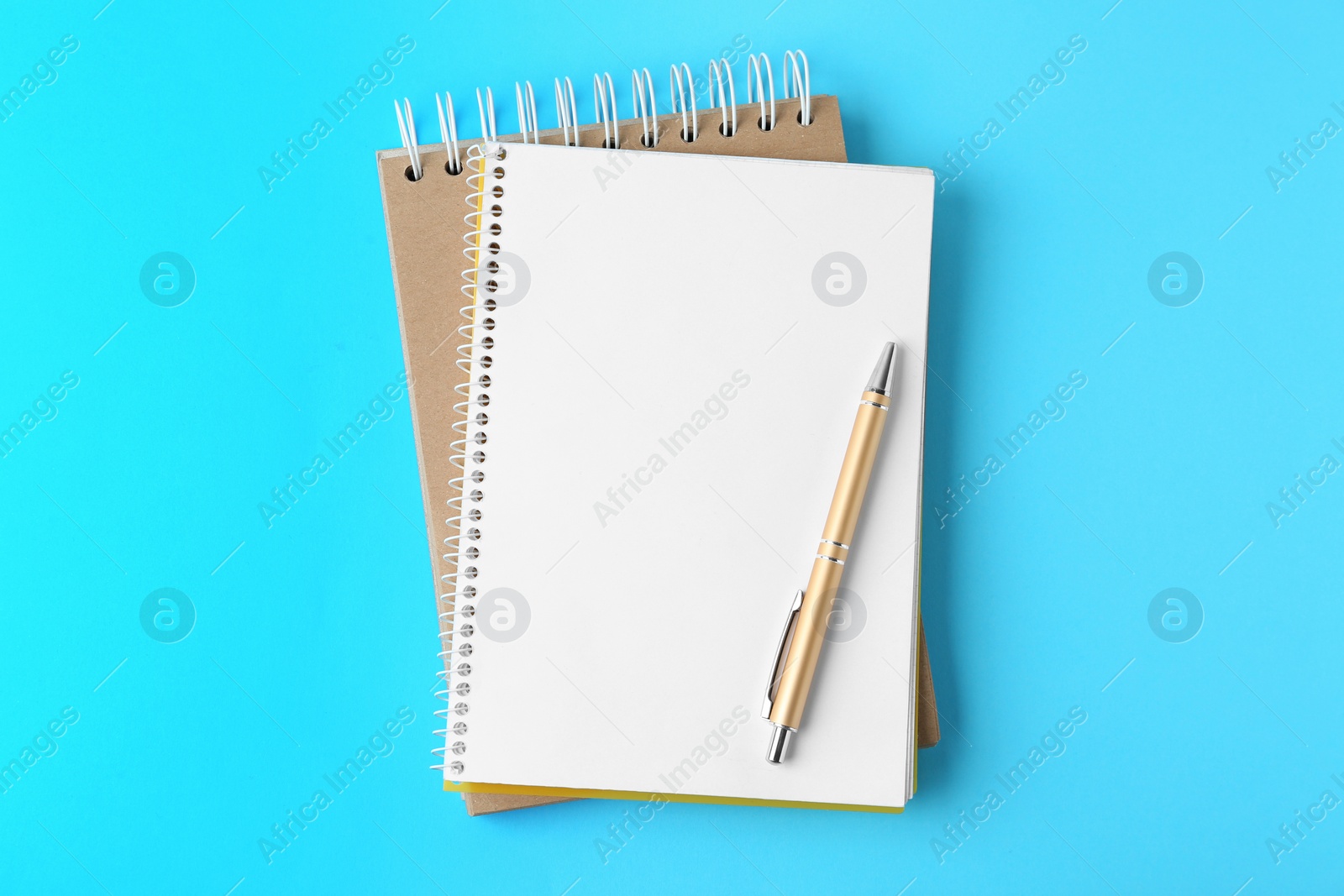 Photo of Notebooks and pen on light blue background, top view