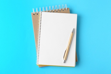 Photo of Notebooks and pen on light blue background, top view