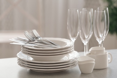 Photo of Set of clean dishware, cutlery and champagne glasses on table indoors