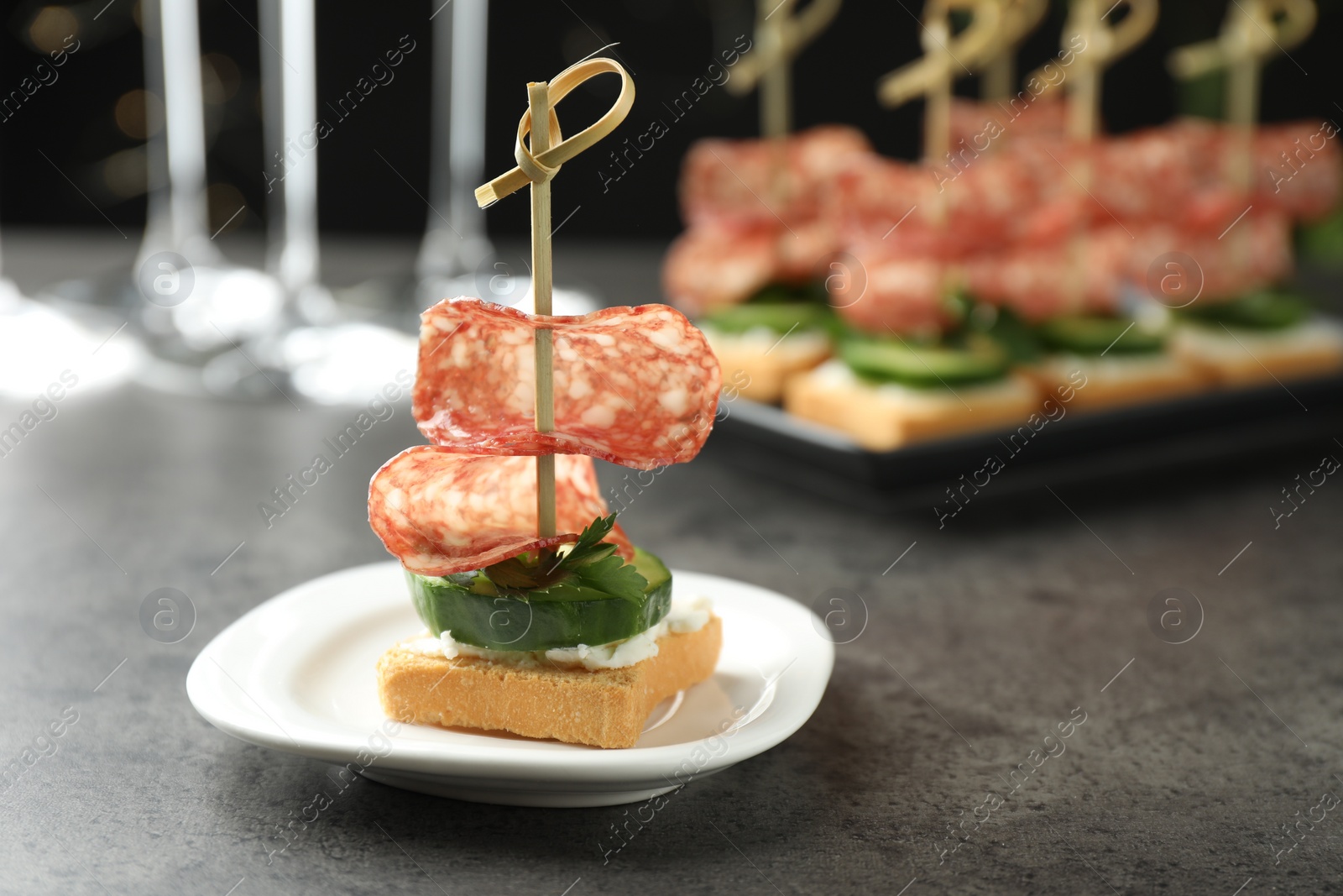 Photo of Tasty canapes with salami, cucumber and cream cheese on grey table. Space for text