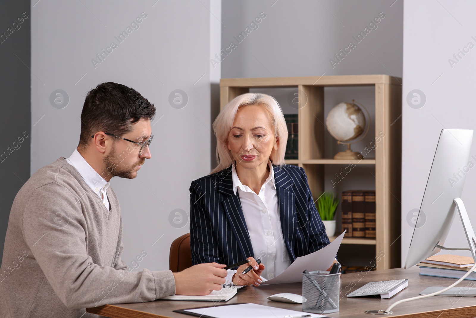 Photo of Boss and employee working at wooden table in office