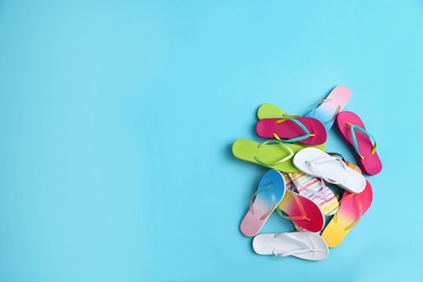 Photo of Heap of different flip flops and space for text on blue background, top view. Summer beach accessories