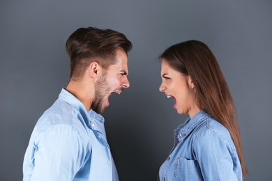 Photo of Young couple having argument on grey background. Relationship problems