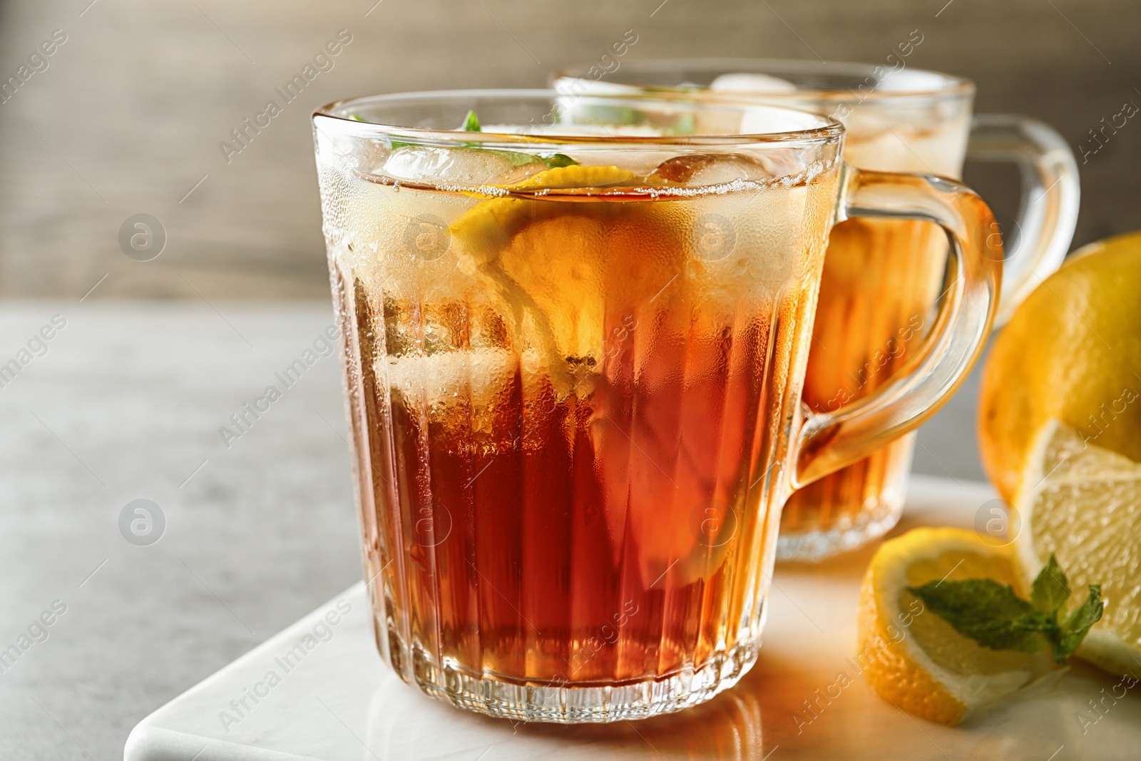 Photo of Cups of refreshing iced tea on table against wooden background