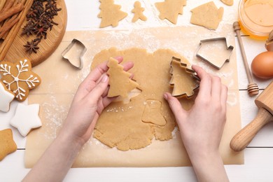 Photo of Woman making Christmas cookies with cutters at white wooden table, top view