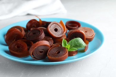 Delicious fruit leather rolls on light table, closeup