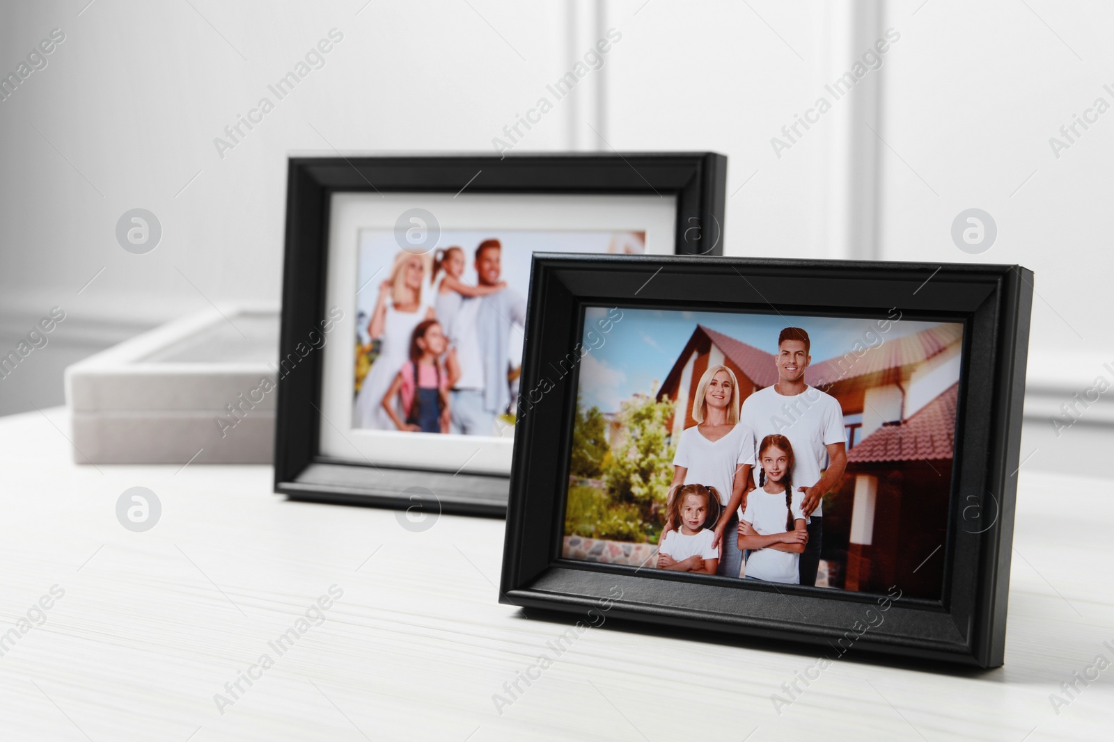 Photo of Framed family photos on white wooden table indoors. Space for text