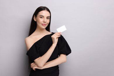 Woman holding blank business card on light grey background. Space for text