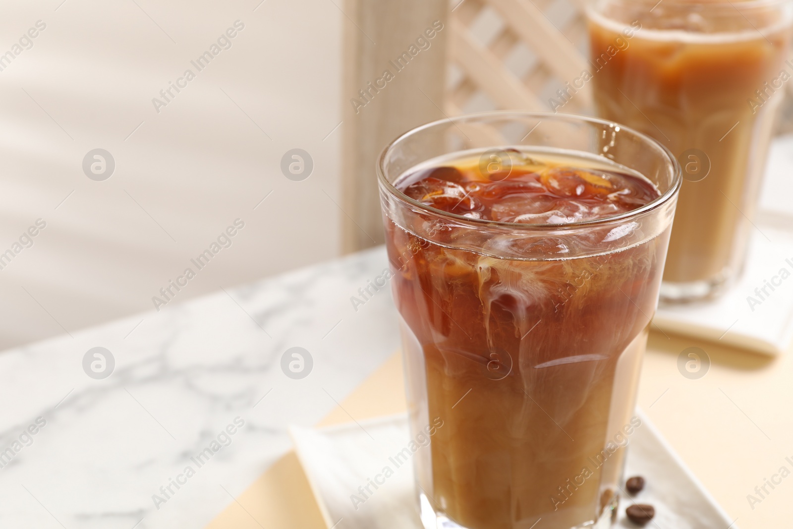 Photo of Refreshing iced coffee with milk in glasses on table, closeup. Space for text