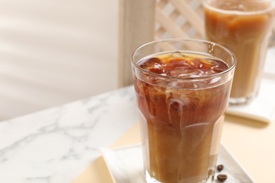 Refreshing iced coffee with milk in glasses on table, closeup. Space for text