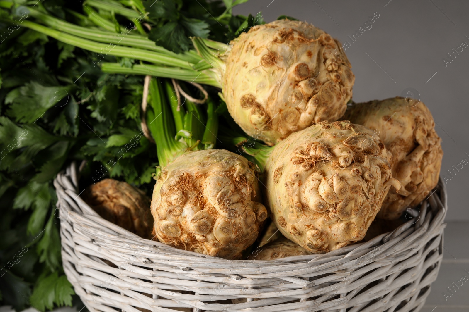 Photo of Fresh raw celery roots in wicker basket, closeup