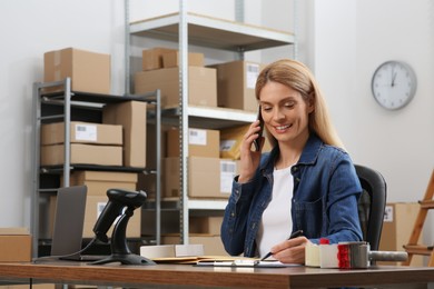 Photo of Seller talking on phone while working in office. Online store