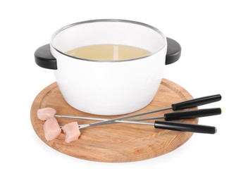 Oil in fondue pot and forks with pieces of raw meat isolated on white