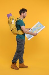 Photo of Man with backpack and map on orange background. Active tourism