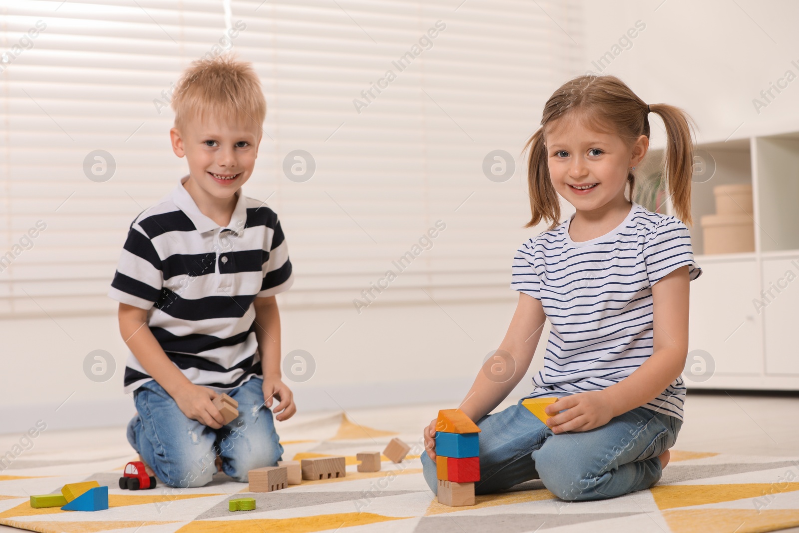 Photo of Little children playing with building blocks indoors. Wooden toys