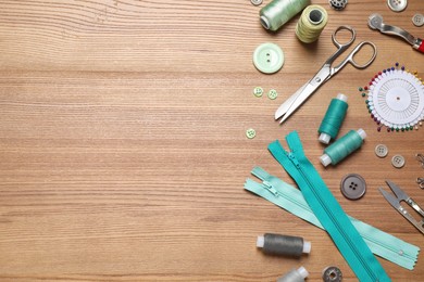 Flat lay composition with different sewing accessories on wooden background. Space for text