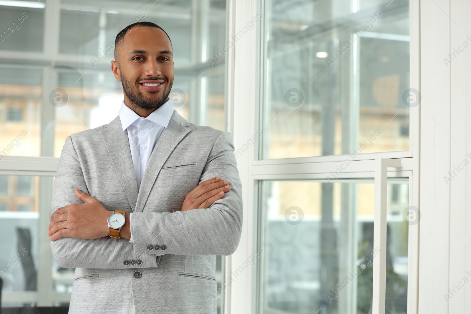 Photo of Happy man with crossed arms in office, space for text. Lawyer, businessman, accountant or manager