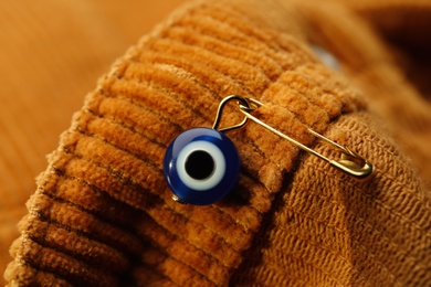 Evil eye safety pin on clothing, closeup