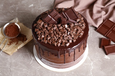 Photo of Freshly made delicious chocolate cake on marble table against grey background