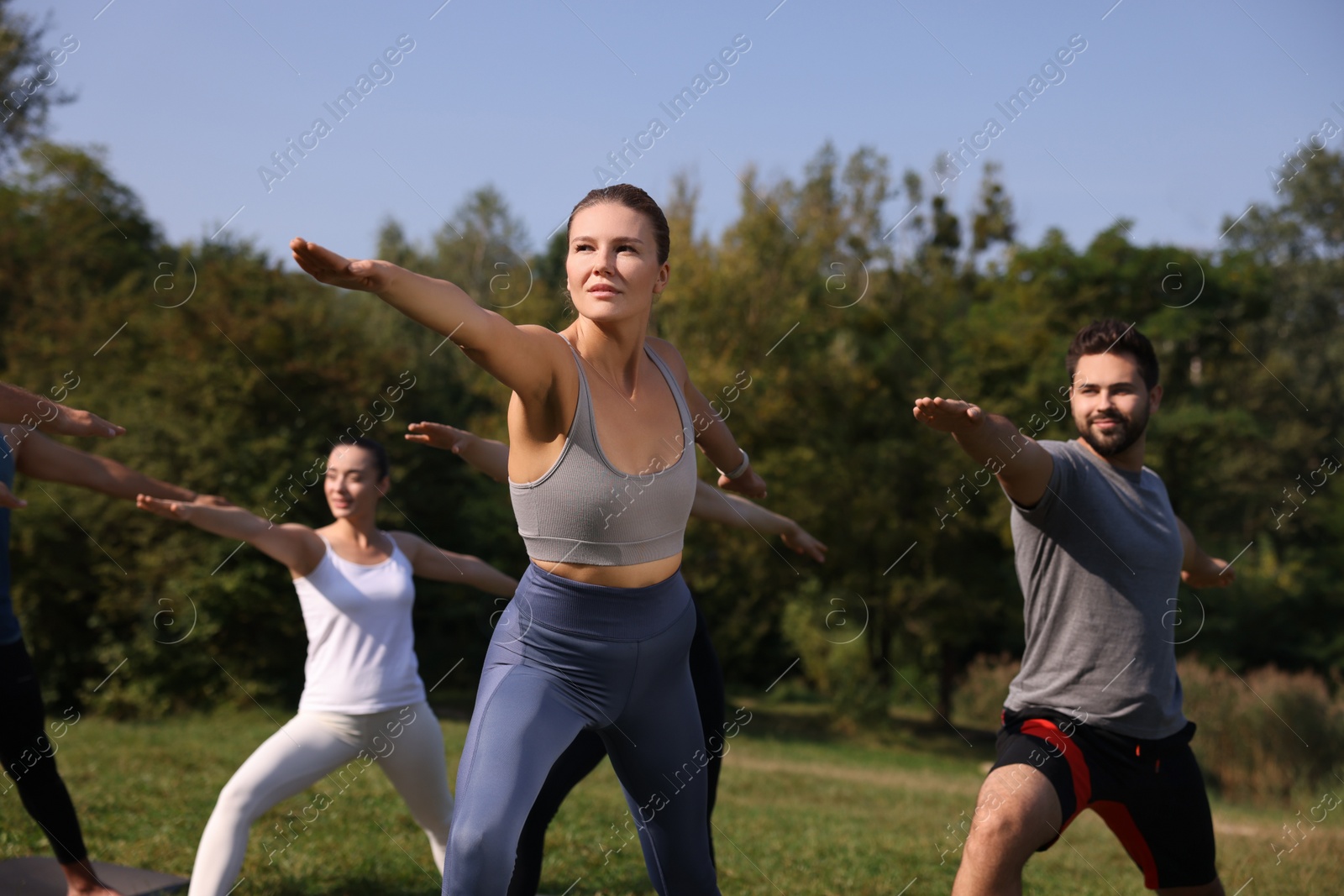 Photo of Group of people practicing yoga in park on sunny day, selective focus