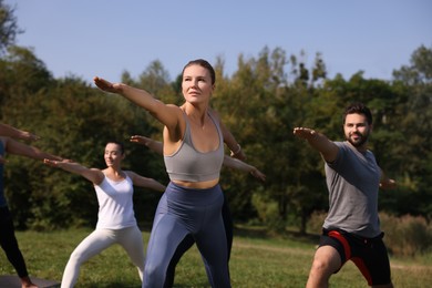 Photo of Group of people practicing yoga in park on sunny day, selective focus