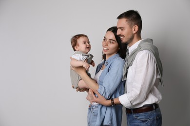 Happy family. Couple with their cute baby on grey background, space for text