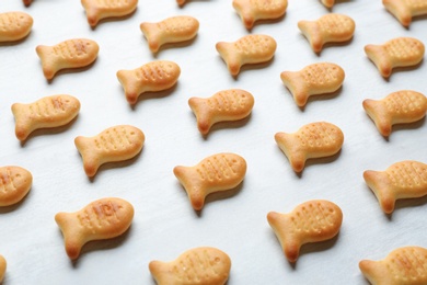 Photo of Delicious goldfish crackers on white table, closeup