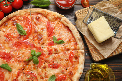Photo of Delicious pizza Margherita and ingredients on wooden table, flat lay