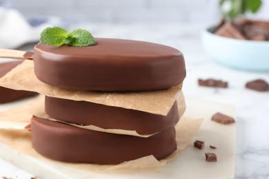 Photo of Delicious glazed ice cream bars with mint on board, closeup