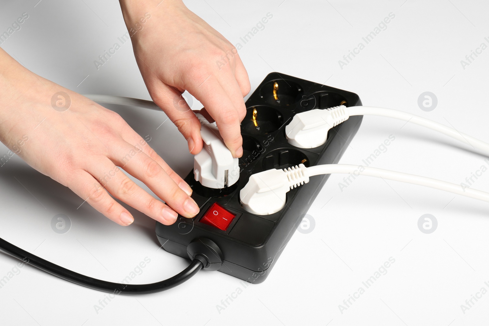 Photo of Woman putting plug into extension cord on white background, closeup. Electrician's equipment