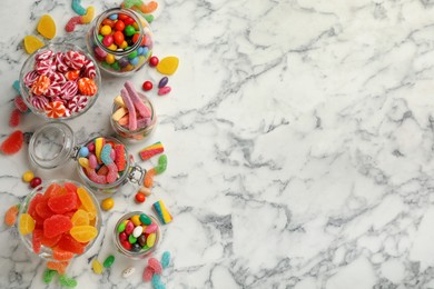 Photo of Jars with different delicious candies on white marble table, flat lay. Space for text